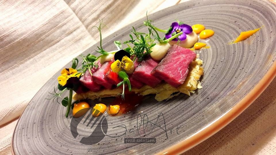 Tataki de vită pe foietaj, cu piure de morcov și flori comestibile.